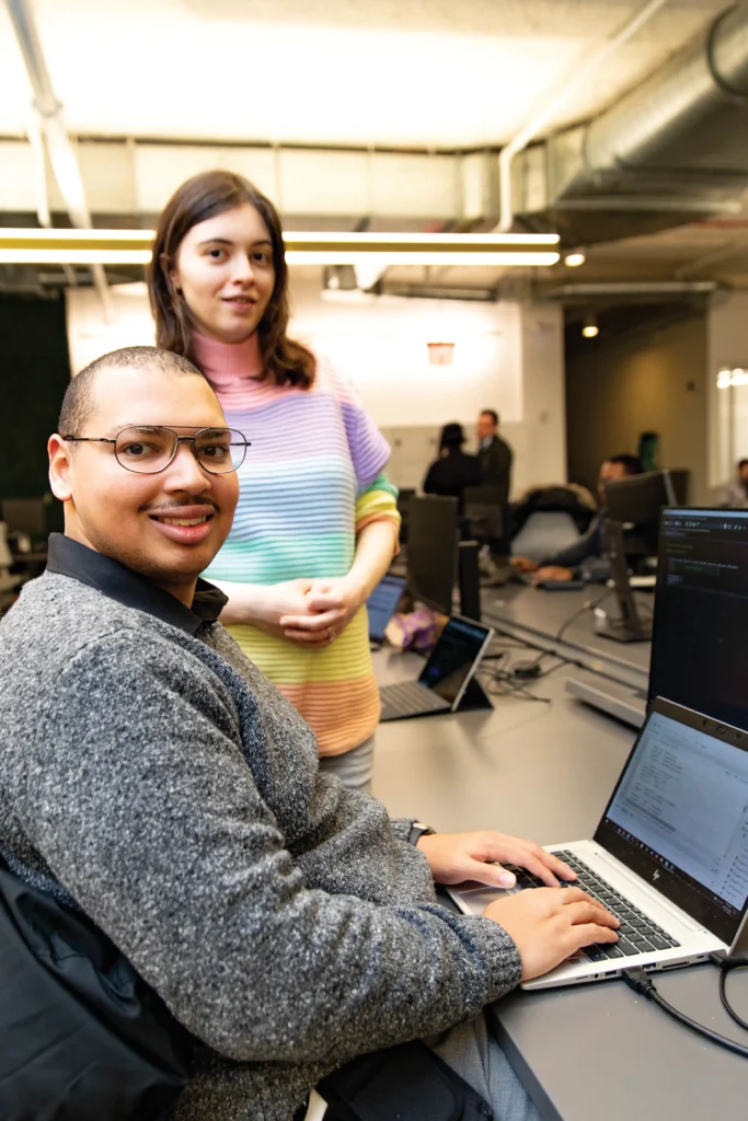 Image of Roberto working at a computer with a woman in the background