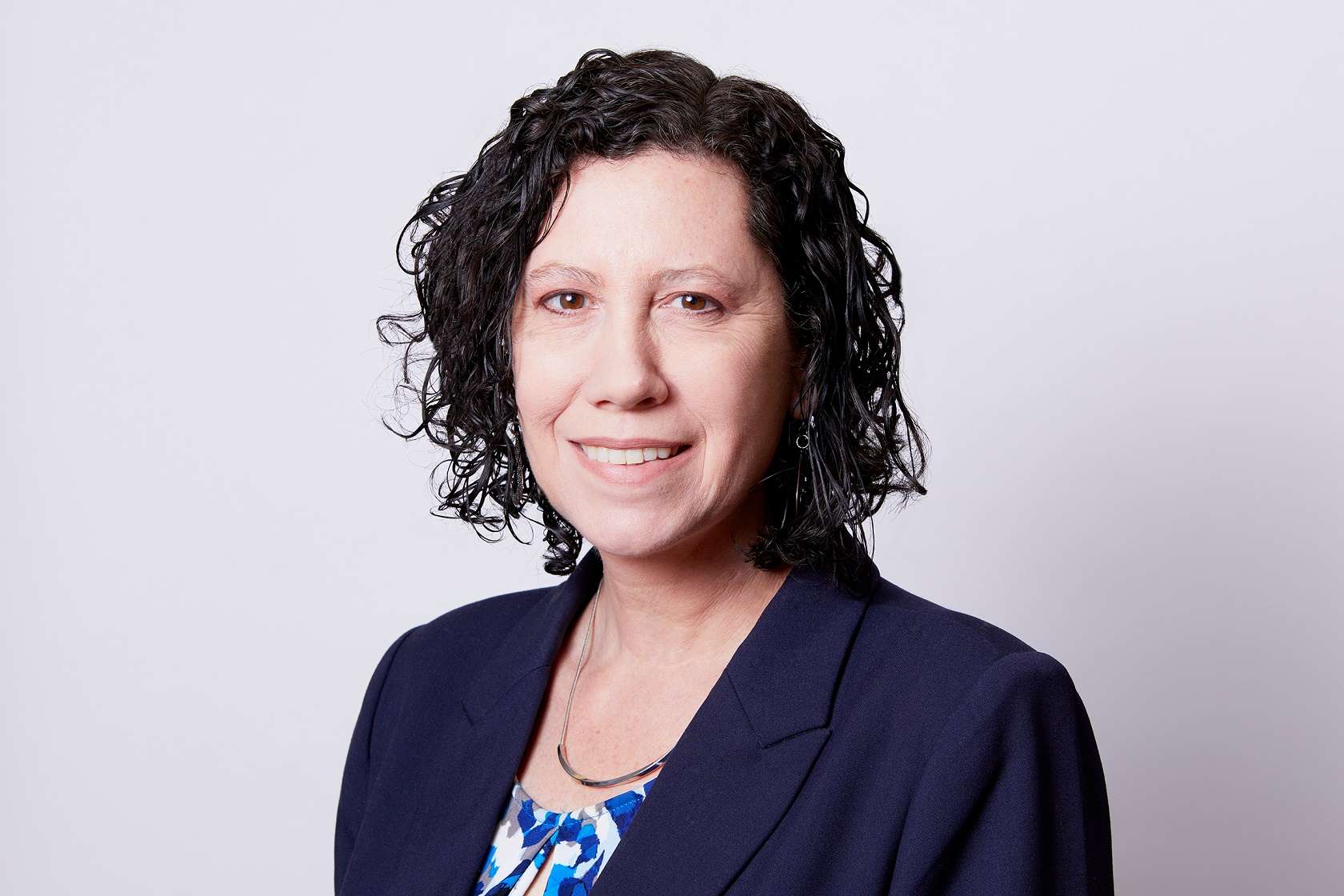 A woman with curly hair wearing a blue blazer